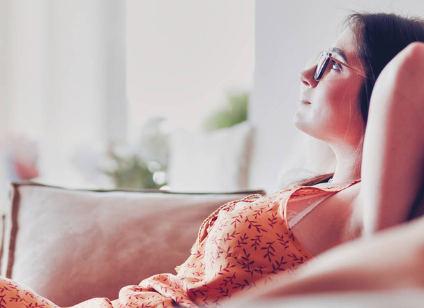 Relaxed woman sitting on a modern sofa at home. - Foto, Imagen