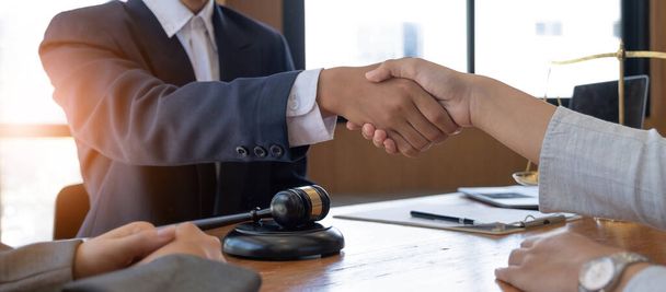 Бізнесмен потискає руки, щоб запечатати угоду зі своїми адвокатами-партнерами або адвокатами, які обговорюють договір
 - Фото, зображення