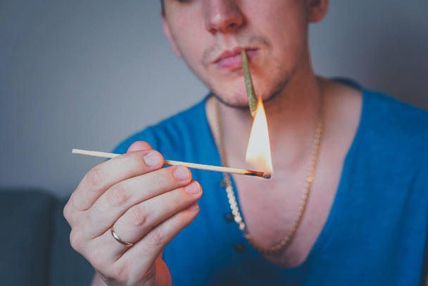 Close-up of adult man lights up with matches and smoking medical marijuana joint. Concept of herbal and alternative medicine - Fotó, kép