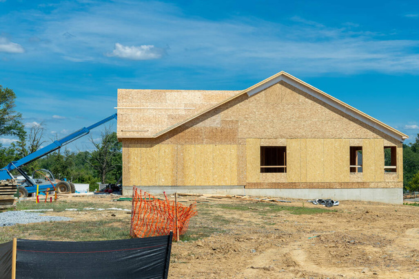 New residential frame house under construction against a blue sky plywood rof wall window - Fotó, kép