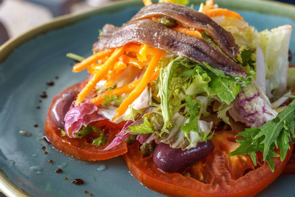 Freshly made salad for lunch or dinner. Healthy food. Fresh green and violet lettuce, anchovies, tomato and olives, virgin olive oil. Vegetarian food. - Fotó, kép