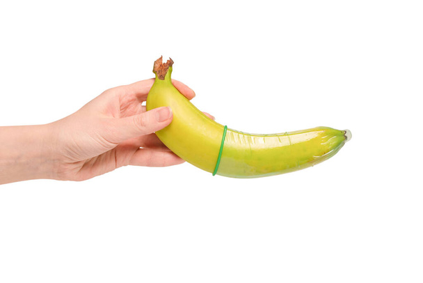 Μια γυναίκα έβαλε προφυλακτικό σε μια μπανάνα. Απομονωμένα σε λευκό φόντο.  - Φωτογραφία, εικόνα