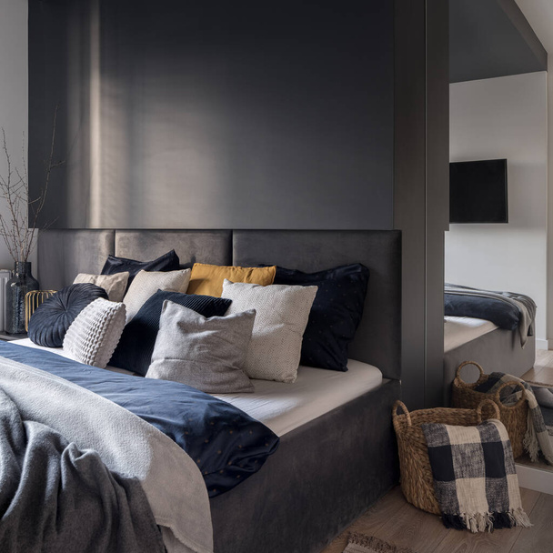 Stylish bedroom with cozy bed with nice bedclothes and pillows, big mirror and decorations - Foto, afbeelding
