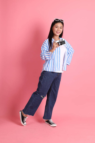The Asian adult woman with casual clothes standing on the pink background. - Foto, imagen