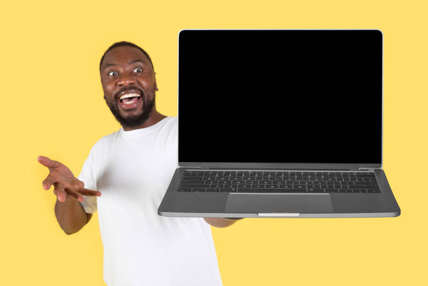 Excited African American Male Showing Laptop Computer With Empty Screen Over Yellow Studio Background. Freelancer Guy Advertising Great Website. Internet Technology Concept. Mockup - Foto, Imagem