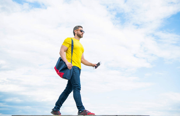 Guy traveler traveling on vacation with travel bag and document sky background, copy space. - Valokuva, kuva