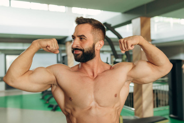 Muscular man in gym. Fitness men with naked torso show his biceps. - Foto, Bild