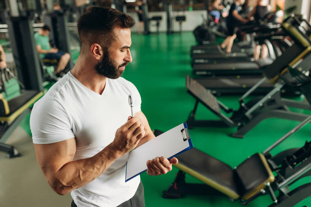 Young coach making a training plan in a gym. Copy space - Fotoğraf, Görsel
