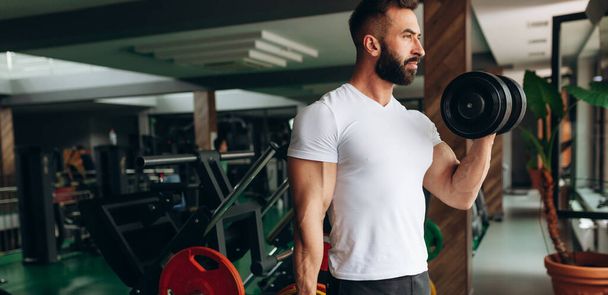 Hübscher Gewichtheber beim Bankdrücken mit der Hantelstange im Fitnessstudio - Foto, Bild