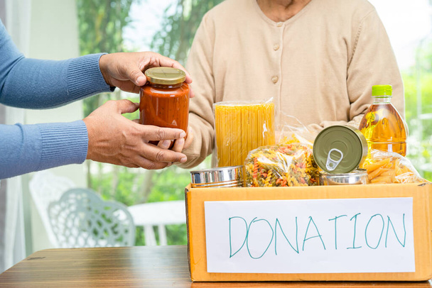 Önkéntesek különböző száraz ételeket tesznek adománydobozba, hogy segítsenek az embereken.. - Fotó, kép