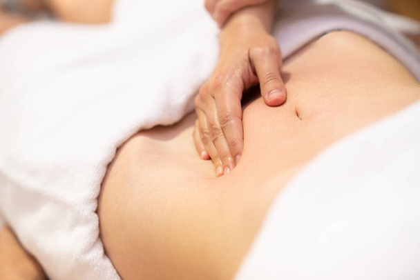 Woman receiving a belly massage in a physiotherapy center. Female patient is receiving treatment by professional osteopathy therapist. - Φωτογραφία, εικόνα