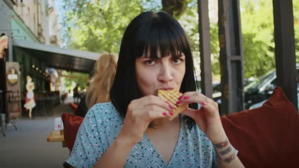 a happy woman enjoys delicious food in a street cafe, rejoices in this taste and smell - Footage, Video