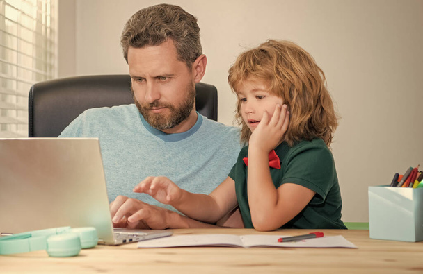 dojrzały mężczyzna nauczyciel lub tata pomaga dziecko syn z pracy domowej w szkole na komputerze, webinar. - Zdjęcie, obraz