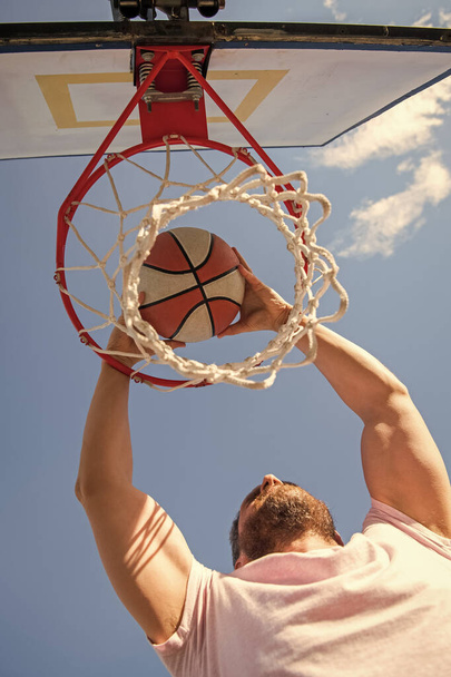 άνθρωπος dunking μπάλα μπάσκετ μέσα από καθαρό δαχτυλίδι με τα χέρια, την επιτυχία του αθλητισμού. - Φωτογραφία, εικόνα