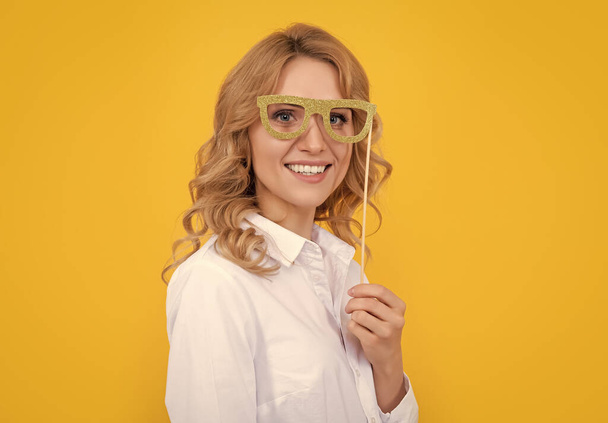 femme souriante avec des lunettes de fête drôles sur fond jaune. - Photo, image