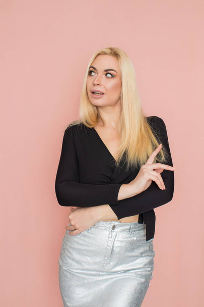 Fashion model woman in fashionable clothes on pink background. Wearing stylish clothing, black blouse, silver skirt. Posing in studio - Φωτογραφία, εικόνα
