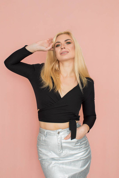 Fashion model woman in fashionable clothes on pink background. Wearing stylish clothing, black blouse, silver skirt. Posing in studio - Φωτογραφία, εικόνα