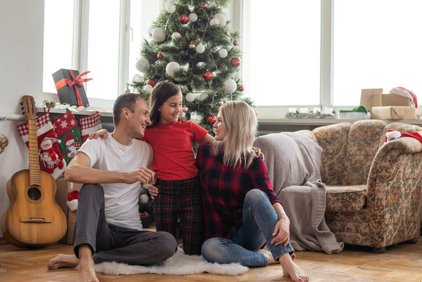Happy family with cute daughter near Christmas tree together at home. - Fotografie, Obrázek