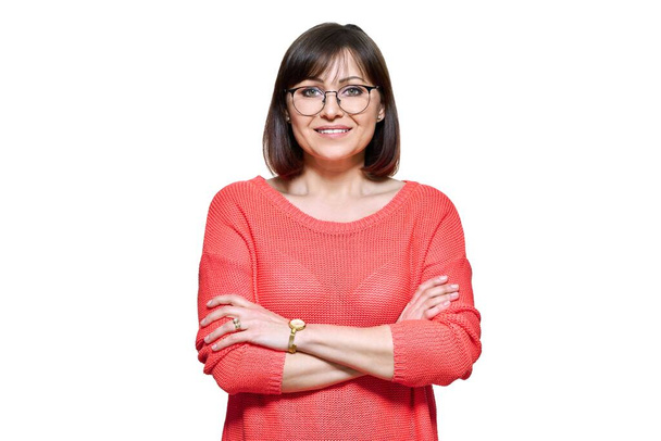 Attractive middle aged woman looking at camera on white isolated background. Smiling confident 40s female with glasses, crossed arms in red casual clothes. Lifestyle confidence calmness mature people - Fotó, kép