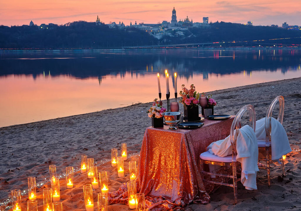 Rande na břehu řeky, zdobený stůl čeká na zamilovaný pár. Městská světla v pozadí, večer Kyjev, Ukrajina. - Fotografie, Obrázek