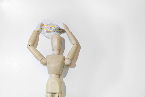 Mannequin Wood Figure carrying an incandescent light bulb. New idea concept. White background - Fotoğraf, Görsel
