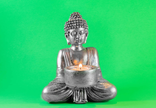 Статуя Будды с зажженной свечой. зеленый экран - Фото, изображение