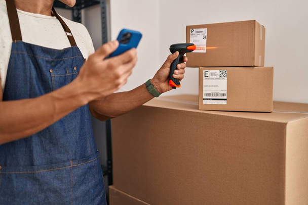 Young hispanic man ecommerce business worker scanning package at office - Photo, Image