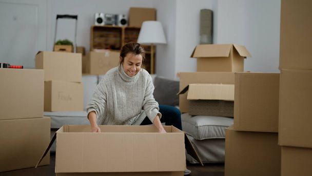 Middle age hispanic woman unboxing package at street - Photo, Image