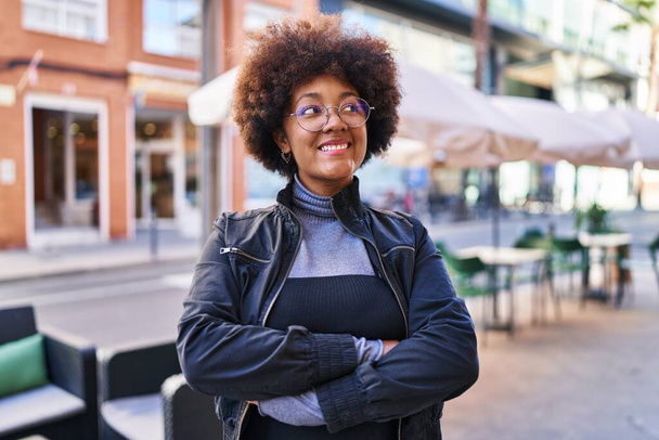 donna afroamericana sorridente fiducioso in piedi con le braccia incrociate gesto in strada - Foto, immagini
