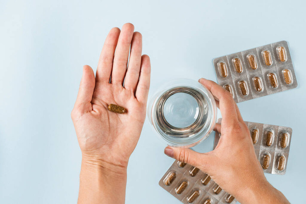 Proper nutrition concept. Holding weight loss pill for diet in hand and ready to drink water. Blister with tablets for dietary. Diet with biologically active supplement - Foto, Imagem