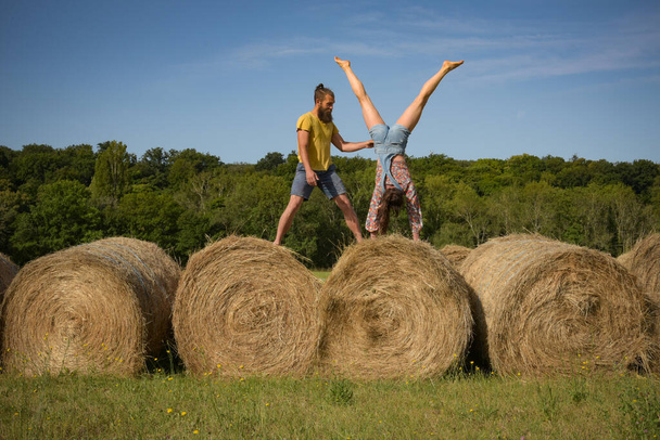 caucasian couple doing stunts on straw bales in France - Foto, afbeelding