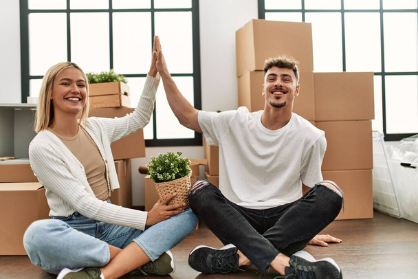 Young caucasian couple smiling happy high five sitting at new home. - Photo, Image