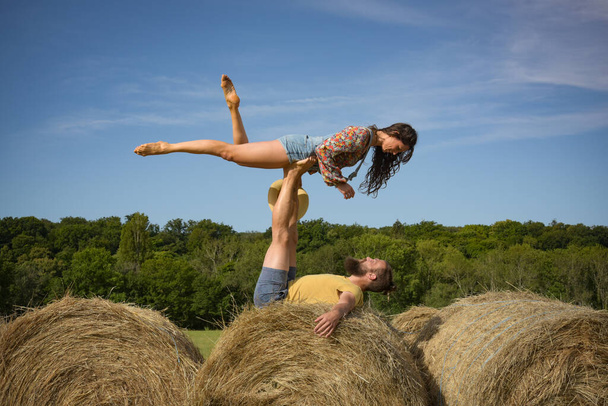 caucasian couple doing stunts on straw bales in France - Foto, afbeelding