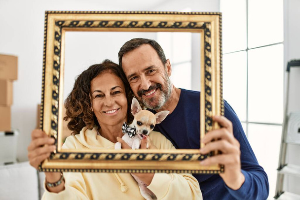 Középkorú spanyol család mosolyog boldog gazdaság üres keret az új otthon. - Fotó, kép