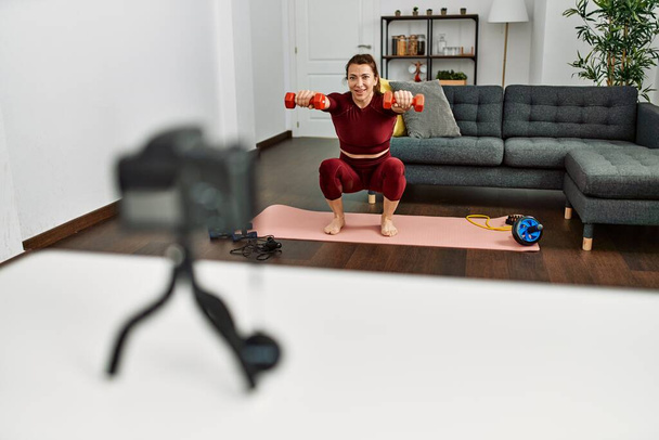 Moyen âge femme sportive caucasienne faisant tutoriel de formation en utilisant la caméra à la maison. - Photo, image