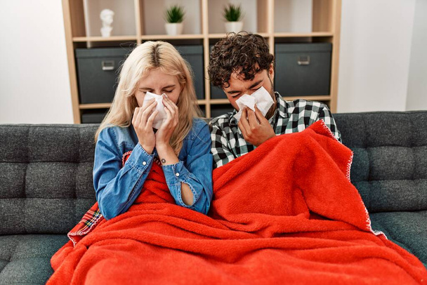 Giovane coppia malata utilizzando tovagliolo sititng sul divano a casa. - Foto, immagini