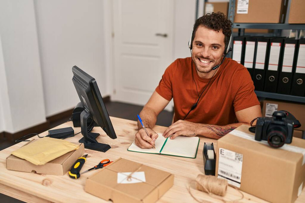Junge hispanische Mann E-Commerce Call Center Agent mit Videoanruf Schreiben auf Notebook im Büro - Foto, Bild