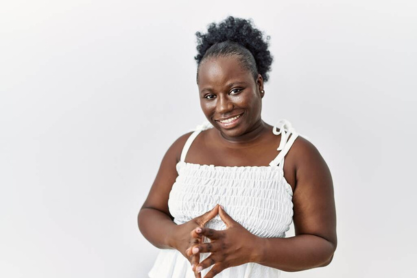 Young african woman standing over white isolated background hands together and fingers crossed smiling relaxed and cheerful. success and optimistic  - Zdjęcie, obraz