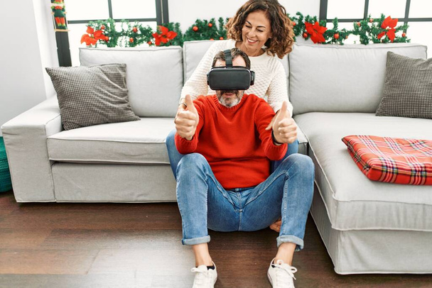Middle age hispanic couple smiling happy sitting on the sofa playing with virtual reality glasses at home. - Valokuva, kuva