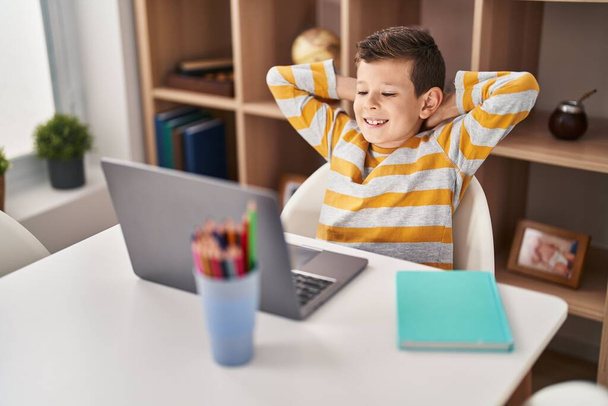 Blond child using laptop sitting on table at home - Zdjęcie, obraz