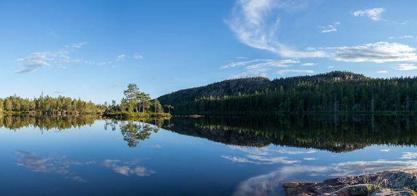 Stunning view of Serene and Reflecting Lake Tarnattvattnen and Remote hiking Resting Cottage in Skuleskogen National Park on a Summertime Evening with gorgeous background of Slattdalsskrevan.  - Foto, immagini