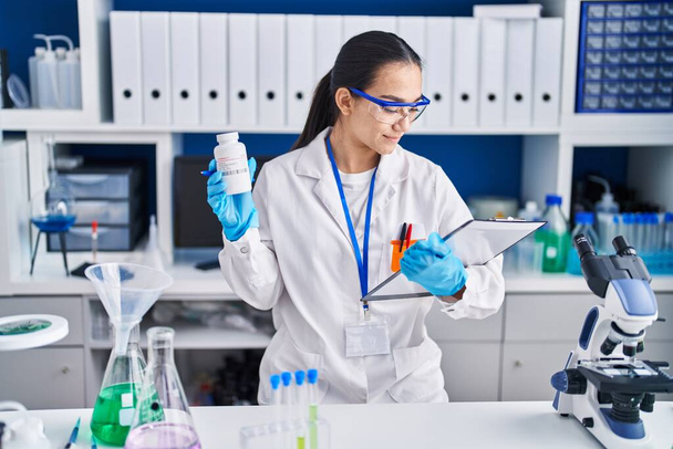 Junge hispanische Wissenschaftlerin hält Pillen im Labor - Foto, Bild