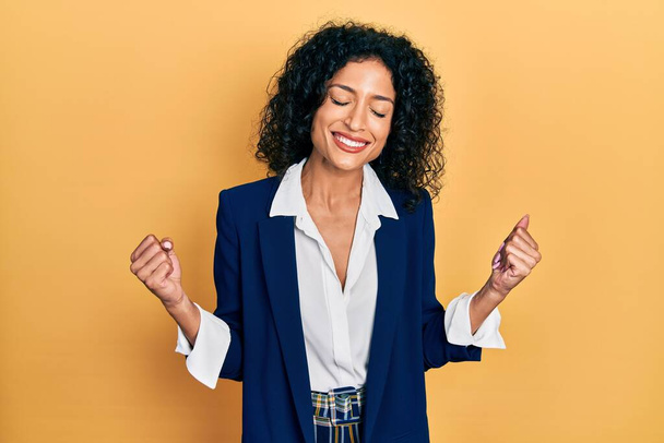 Young latin girl wearing business clothes very happy and excited doing winner gesture with arms raised, smiling and screaming for success. celebration concept.  - Foto, Bild
