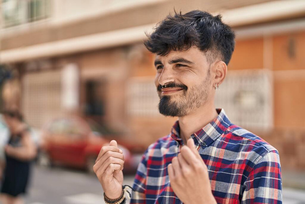 Young hispanic man smiling confident doing spend money gesture at street - Fotografie, Obrázek