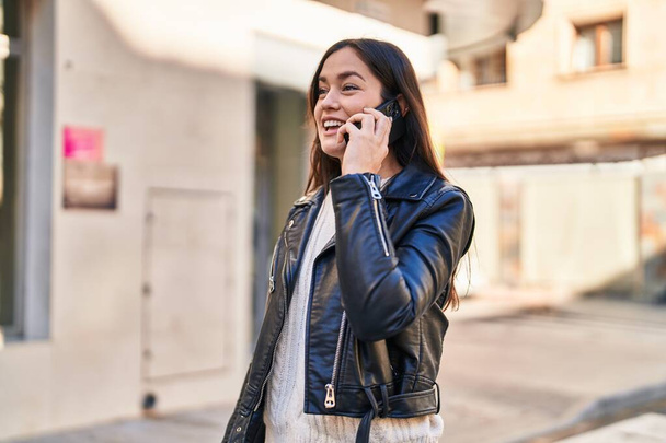 Mladá žena se usmívá sebevědomě mluvit na smartphone na ulici - Fotografie, Obrázek