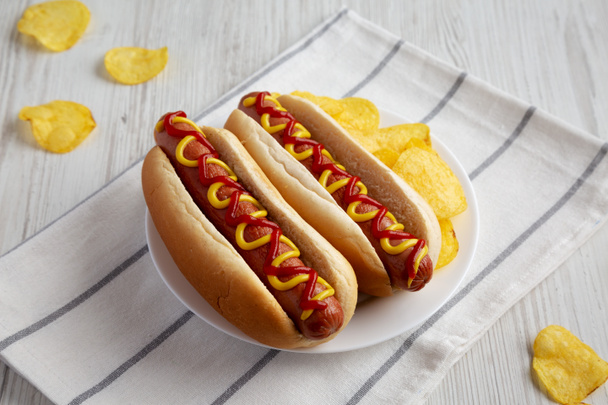 Homemade Hot Dog with Ketchup and Yellow Mustard with Chips on a Plate, low angle view.  - Foto, Imagem