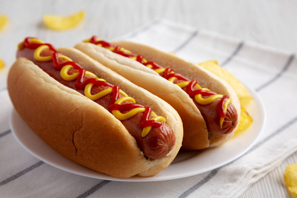 Homemade Hot Dog with Ketchup and Yellow Mustard with Chips on a Plate, low angle view. Close-up. - Foto, Imagem