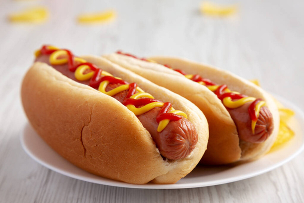 Homemade Hot Dog with Ketchup and Yellow Mustard with Chips on a Plate, side view. Close-up. - Foto, afbeelding