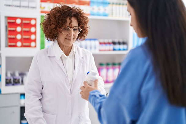 Дві жінки фармацевт і клієнт призначають таблетки в аптеці
 - Фото, зображення