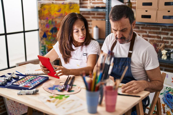 Orta yaşlı erkek ve kadın sanatçılar sanat stüdyosunda dokunmatik kağıt kullanarak defter çiziyorlar. - Fotoğraf, Görsel